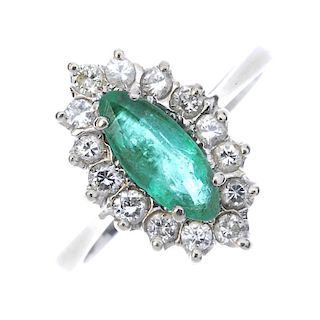 An emerald and diamond cluster ring. The marquise-shape emerald, within a brilliant-cut diamond surr