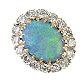 An opal doublet and diamond cluster ring. The oval opal doublet cabochon, within a brilliant-cut dia