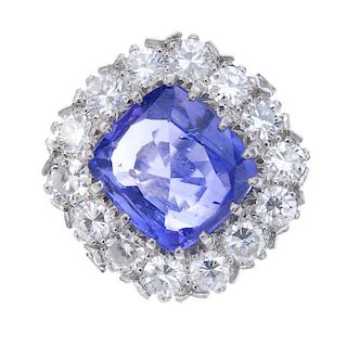 A sapphire and diamond cluster ring. The rectangular-shape sapphire, within a circular-cut diamond s