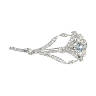 A mid 20th century aquamarine and diamond flower brooch. The cushion-shape aquamarine and brilliant-