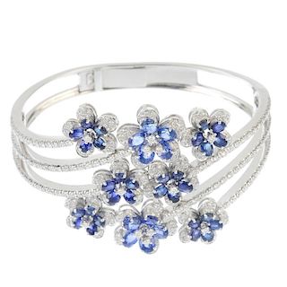 A sapphire and diamond hinged bangle. Designed as a series of oval-shape sapphire and brilliant-cut