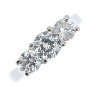 A platinum diamond three-stone ring. The brilliant-cut diamond, with similarly-cut diamond sides, to