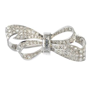 A diamond bow brooch. The brilliant and circular-cut diamond bow, gathered by a tapered baguette-cut