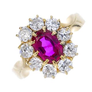 A Burmese ruby and diamond cluster ring. The oval-shape ruby, within a circular-cut diamond surround