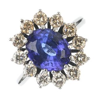 A tanzanite and diamond cluster ring. The oval-shape tanzanite, within a brilliant-cut diamond surro