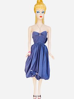 Life size Barbie mannequin, she is wearing blue dress with poke a dots. She has some paint rubs on fingers, left shoulder, back, paint chips off toes 