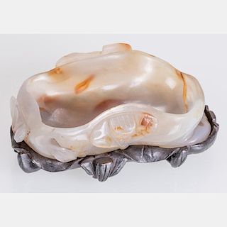 A Chinese Carved Agate Lotus Leaf Form Washer on a Carved Hardwood Stand.
