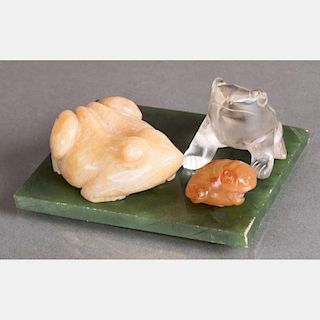 A Group of Three Carved Hardstone Frog Figures on a Green Marble Slab,