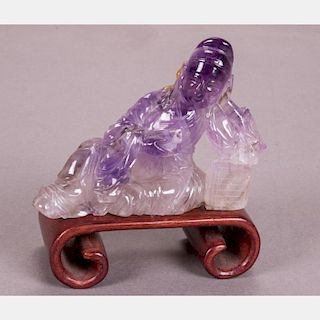 A Chinese Carved Amethyst of a Reclining Figure on a Carved Hardwood Stand.