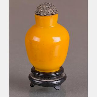 A Yellow Peking Glass Snuff Bottle with Silver Stopper on Carved Hardwood Stand.