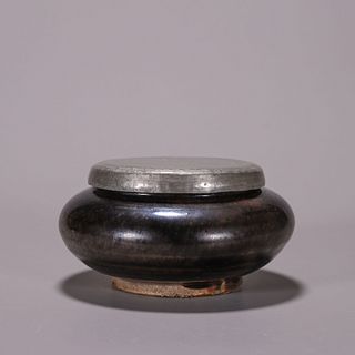 A black glazed porcelain jar with silver lid