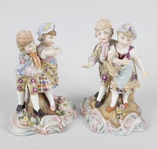 A pair of German porcelain figures of couples. Each modelled as a boy and girl, one girl holding a b