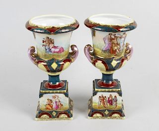 A pair of Vienna porcelain urns, each having twin short scrolled handles and raised upon stepped ped