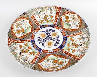 An early 20th century Japanese porcelain charger, having central circular panel of flowers, within a