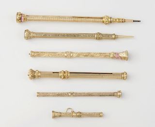 A group of gilt sleeved pencils, the largest with engine turned body, leading to a monogrammed inset
