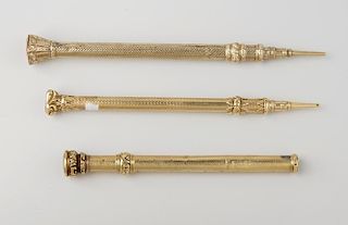 Three yellow metal propelling pencils, each with seal-top terminal and textured body, largest 4.5, (