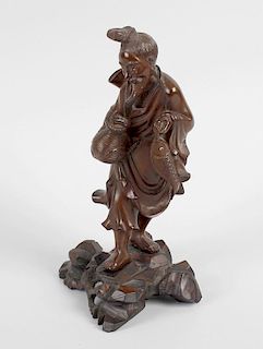 An oriental carved hardwood study of a fisherman, standing and holding a basket and his catch, upon