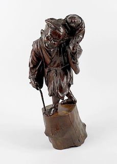 A large Japanese Meiji period carved hardwood study of a peasant walking and supported by a cane, ca