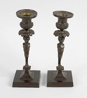 A pair of Regency bronze candlesticks, each having campana socket above a formalised leaf border lea