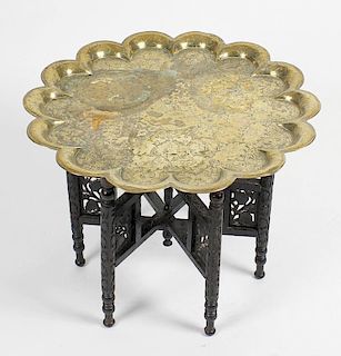 An Eastern brass topped table on folding carved hardwood stand, together with a similar Eastern tray