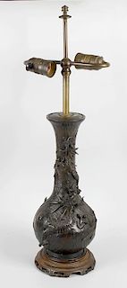 A Japanese bronze vase, of tall bottle form decorated in high relief with dragons upon a waved groun