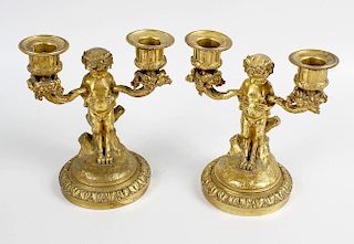 A pair of 19th century ormolu twin-branch candlesticks, each modelled as a young satyr seated upon a
