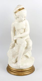 A Belgian plaster figure of a maiden. Early 20th century, modelled as a seated naked female wearing