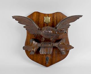 A carved late 19th century wooden study of an eagle, mounted upon a later mahogany finished wall han