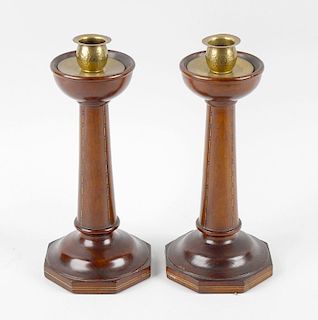 A pair of Arts & Crafts turned wooden candlesticks, each having hammered brass socle raised upon inl