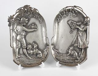A pair of early 20th century WMF pewter wall plaques, each of oval dished form, one decorated with a