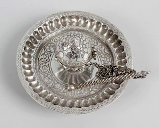 A 19th century Persian white metal opium dish, having domed hinged cover with attached chain leading