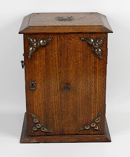 An early 20th century oak smokers cabinet. Having applied copper fittings to the exterior and single