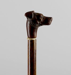 A Victorian walking stick, having carved wooden terrier's head terminal with inset glass eyes, leadi