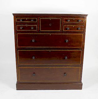 A tall mahogany crossbanded chest of drawers. The central deep drawer flanked by twin columns of two