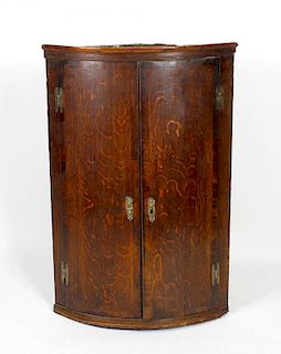 A late George III oak and mahogany bow-front hanging corner cupboard. Circa 1800, with a pair of mah