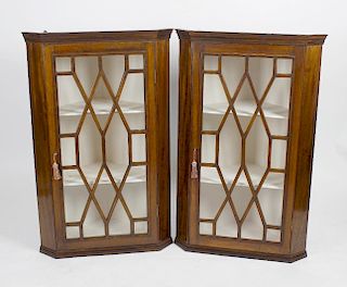 A pair of mahogany corner cupboards. Each having astragal glazed hinged door opening to a painted in