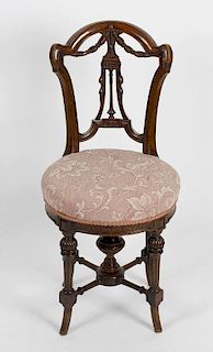 An unusual late Victorian carved walnut music chair, the curved open back with bell flower swags and