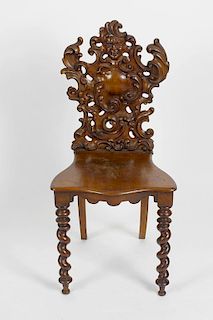 A 19th century carved fruitwood hall chair, the back headed by a 'Green Man' mask over deeply carved