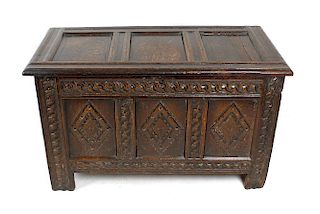 A 17th century oak coffer or bedding chest. The hinged top of three recessed panels within channel-m