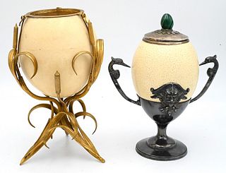 Two Ostrich Egg Table Ornaments, to include a Anthony Redmill silver-plate mounted egg having malachite finial; along with a French egg mounted on scr