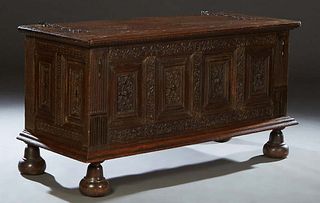 French Provincial Carved Oak Louis XIII Style Coffer, 18th c., the stepped top with long wrought iron strap hinges over a front panel with leaf and sc
