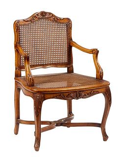 French Louis XV Style Carved Cherry Fauteuil, 20th c., the arched curved caned back over a bowed caned seat flanked by leaf carved arms, on like carve
