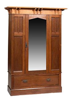 English Arts and Crafts Carved Oak Armoire, c. 1910, the rectangular peaked crown over a central peaked beveled mirror door, on a base with a deep dra