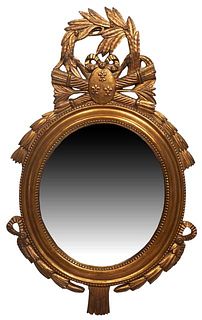Louis XVI Style Carved Giltwood Mirror, 20th c., with a pierced leaf, torch and quiver surmount, over a beaded frame around an oval plate, the bottom 