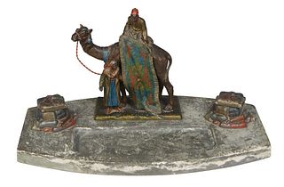 Bergman Style Cold Painted Spelter Arabic Inkwell, early 20th c., with an Arab rug merchant and camel behind two lidded inkwells with white porcelain 