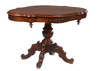 French Carved Cherry Center Table, c. 1870, the stepped edge tortoise shaped top over a wide finialed skirt, with a drawer on each long side, on a tur
