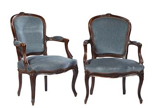 Pair of French Louis XV Style Carved Oak Fauteuils, 20th c., the arched floral carved crest rail over a curved cushioned back, to a bowed cushioned se