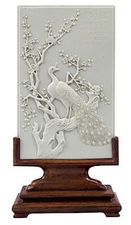 A WHITE BISCUIT GLAZED PORCELAIN PLAQUE WITH A PEACOCK AND PRUNUS, 20TH CENTURY