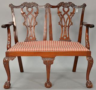 Custom mahogany double chair back settee with open carved backs set on carved cabriole legs ending in ball and claw feet (one knee r...