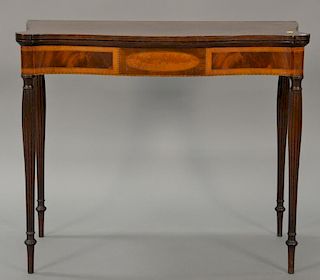 Sheraton mahogany game table having inlaid edges over burlwood oval center medallion panel, hinged top on reeded legs. 
ht. 29 in.; ...